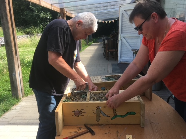 Deux participants assemblent un hôtel à insectes en bois et matériaux naturels.
